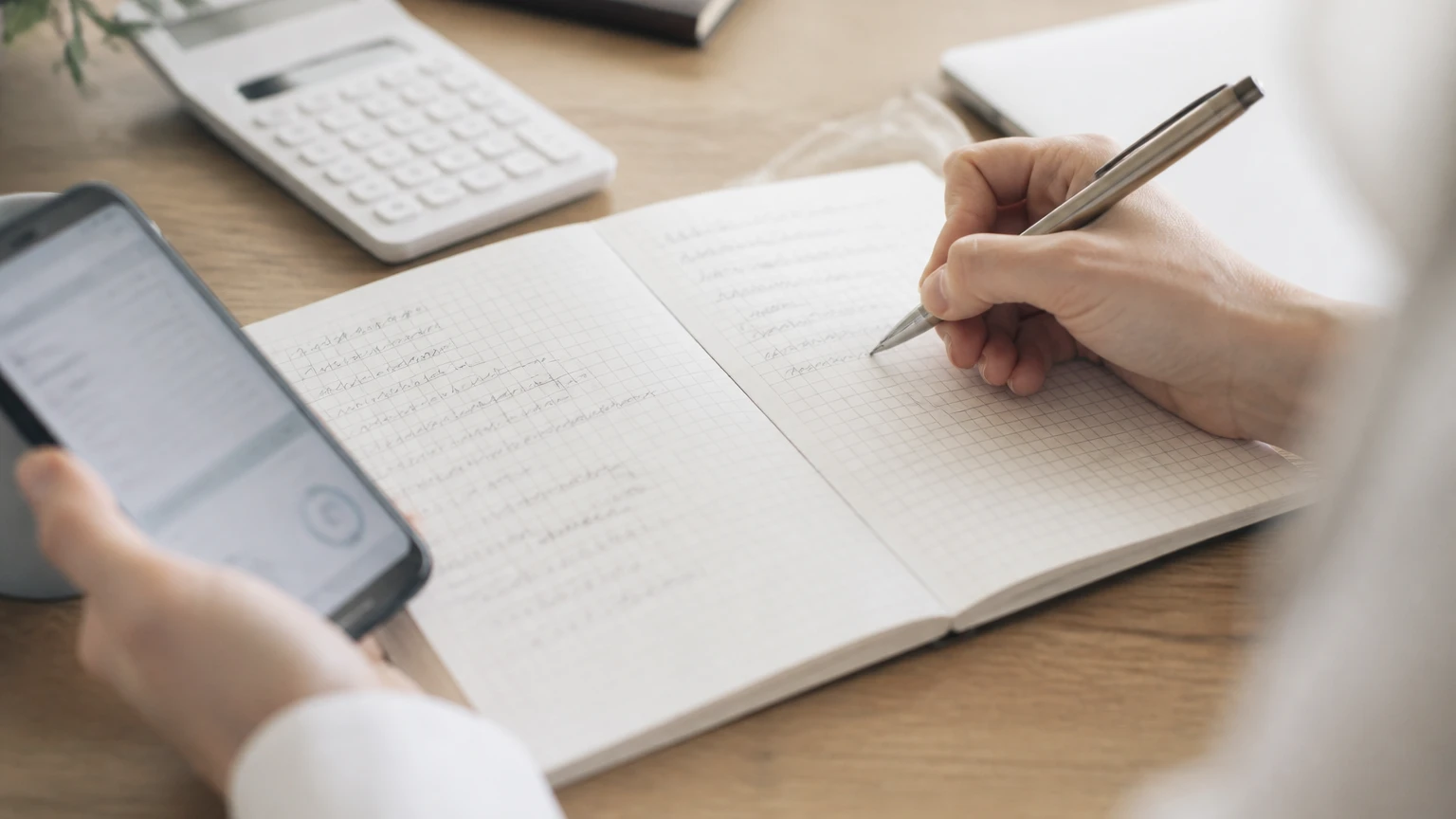 ノートに2列で書き出して料金を比較している手元