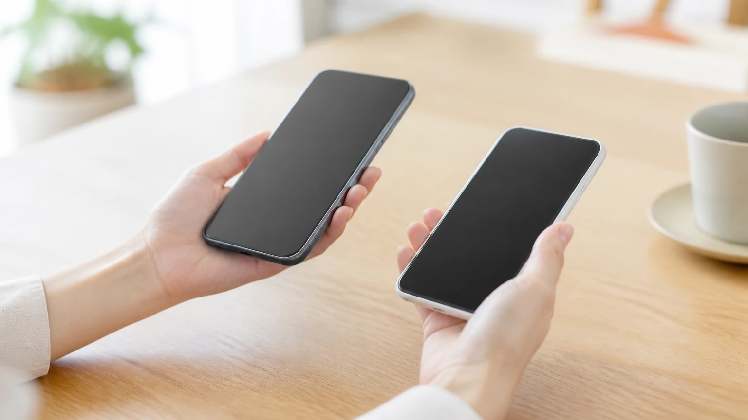 2台のスマートフォンを両手に載せて重さを比べる手元