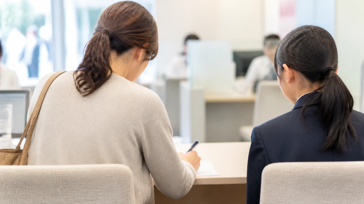 窓口で書類に記入する保護者と子ども