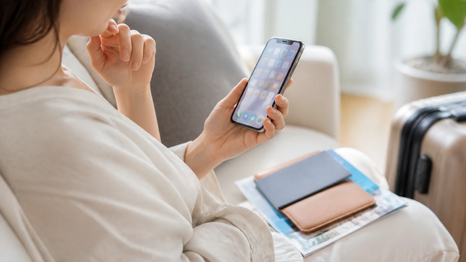 海外旅行の準備中にスマートフォンでサービスを探す女性