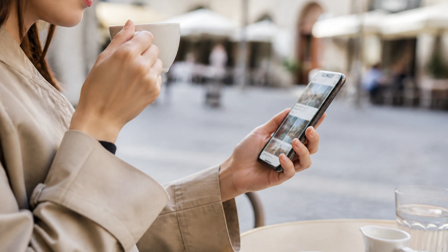 海外のカフェでスマートフォンを使ってくつろぐ女性